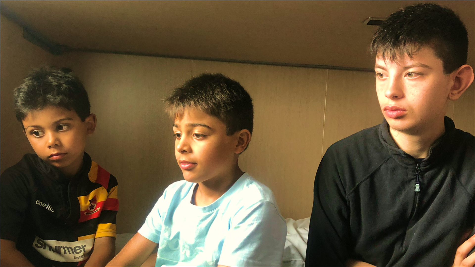 Three boys sitting together, illustrating the dilemma of choosing a safe first phone for children aged 5-12